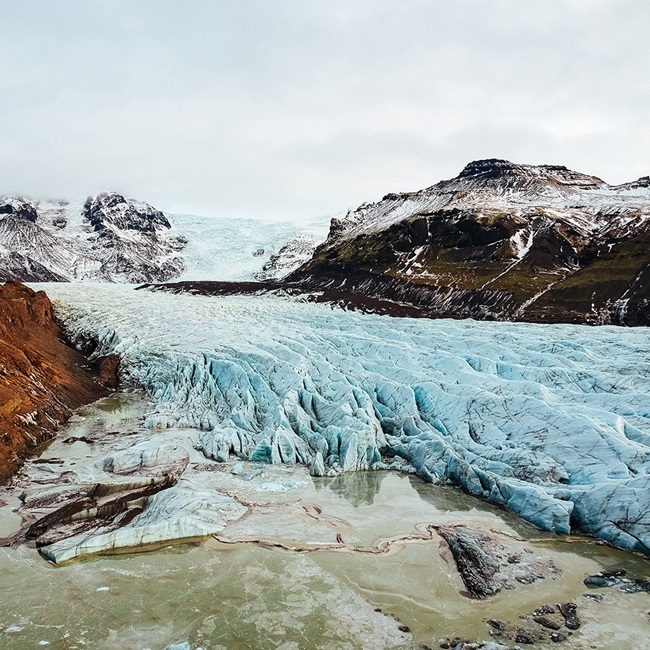 Glacier with sea and mountains in background