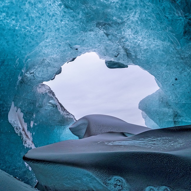 Looking out of an ice cave surrounded by blue ice. 