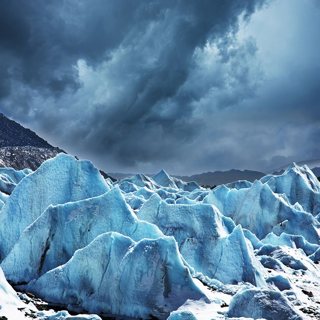 jagged ice edge of a glacier with dark dramatic sky above