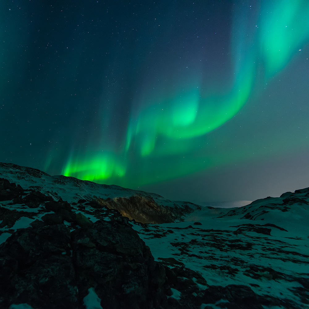 Snowy mountainside with northern lights in background