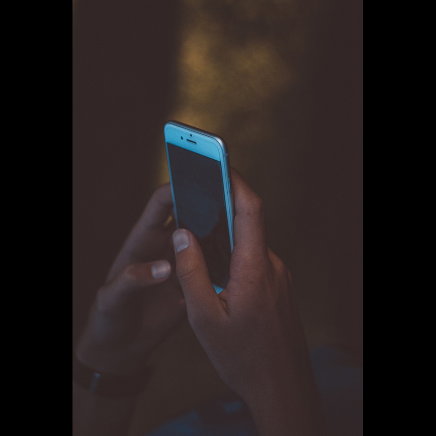 Dark image with person using phone and dark screen