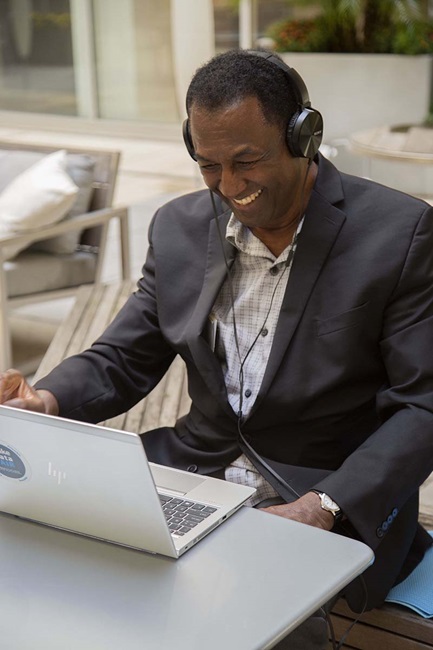 man smiling at computer with headphones on