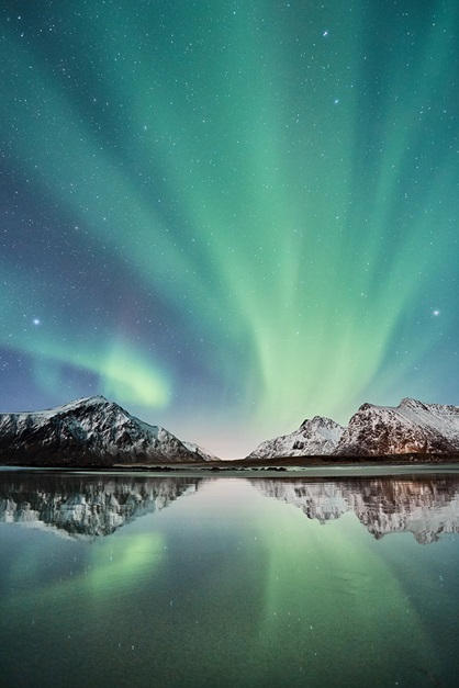 Aurora borealis with snow covered mountains and reflection in water