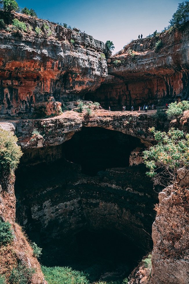 People standing outside of large cavern