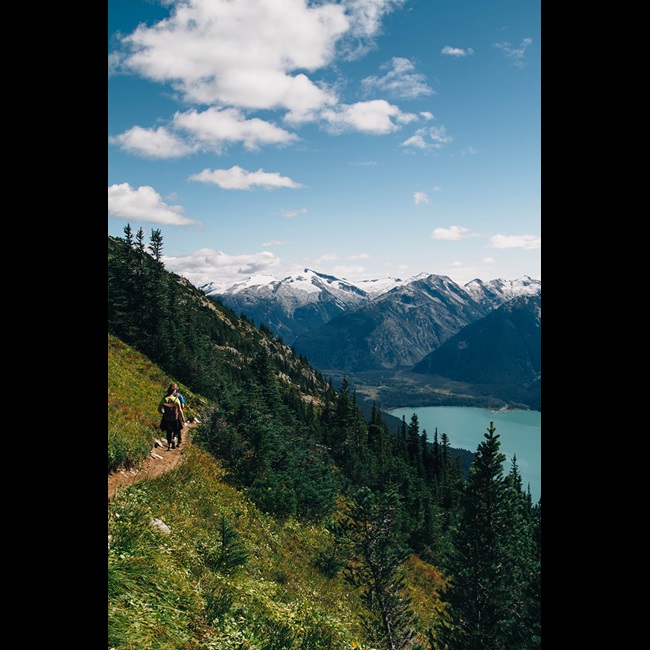 People hiking up side of mountain with lake
