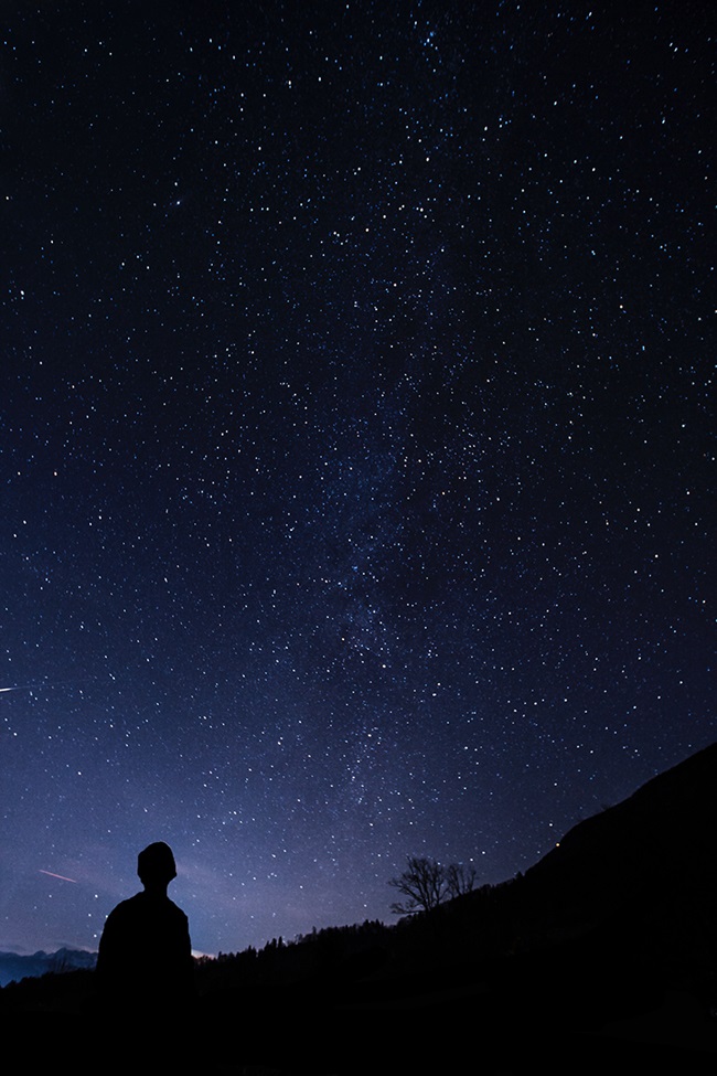 Person silhouetted looking up at stars