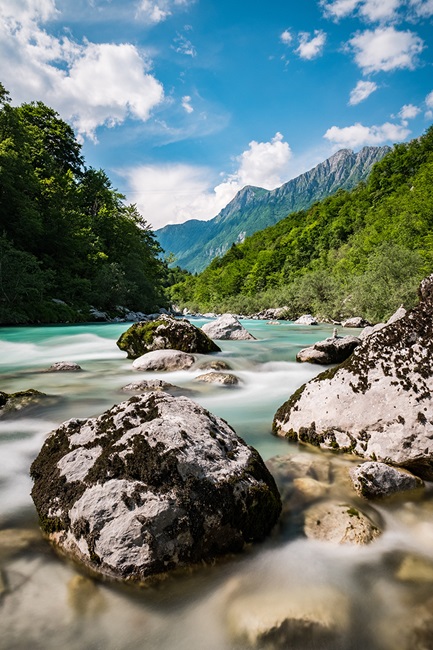 River flowing over rocks with mountains in background, Slovenia