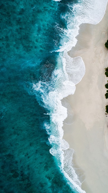 Vertical image of waves crashing on a sandy beach