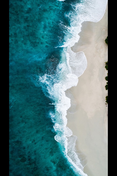 Vertical image of waves crashing on a sandy beach