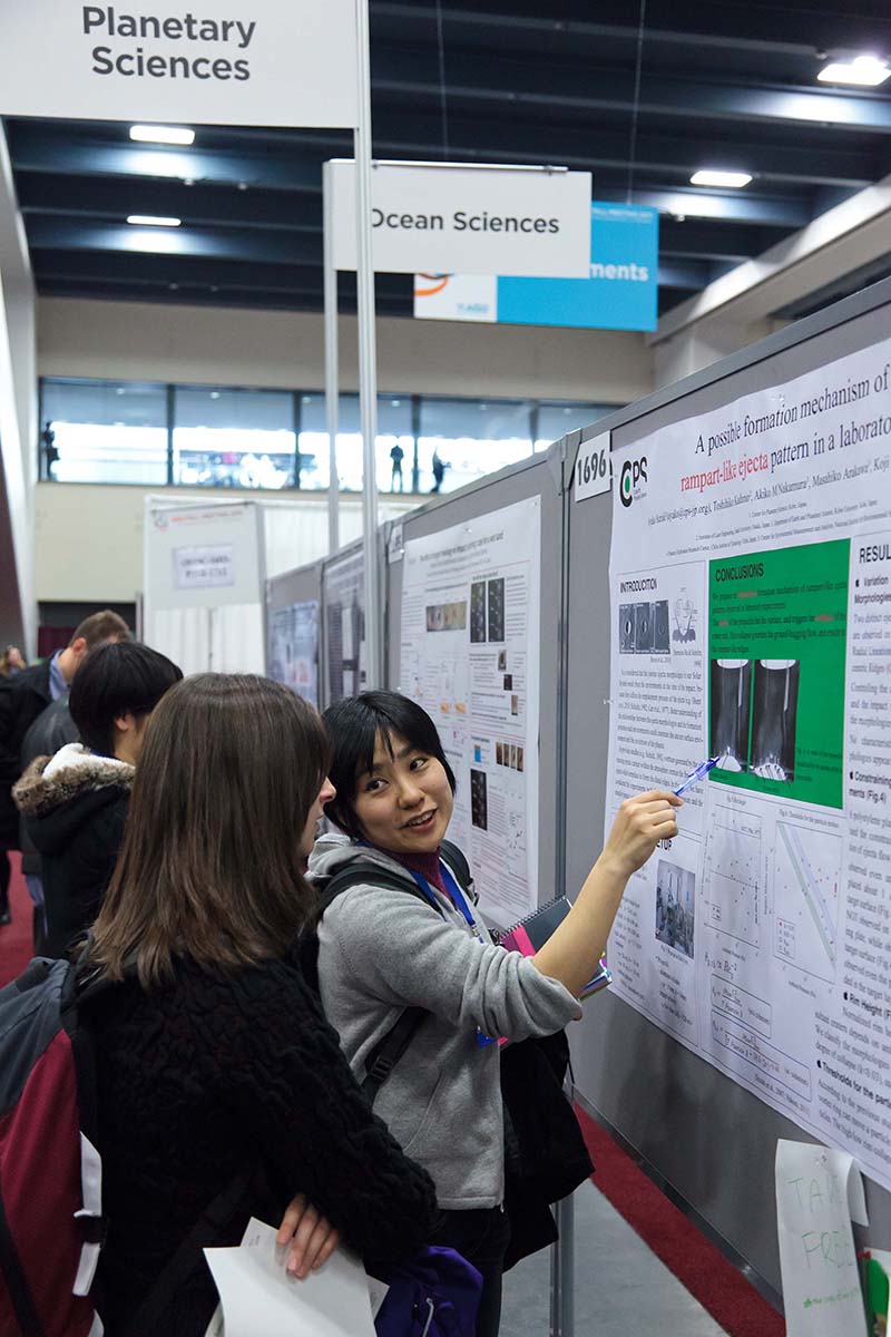 woman explaining poster to woman in the Planetary Sciences section of Poster Hall woman explaining poster to woman in the Planetary Sciences section of Poster Hall