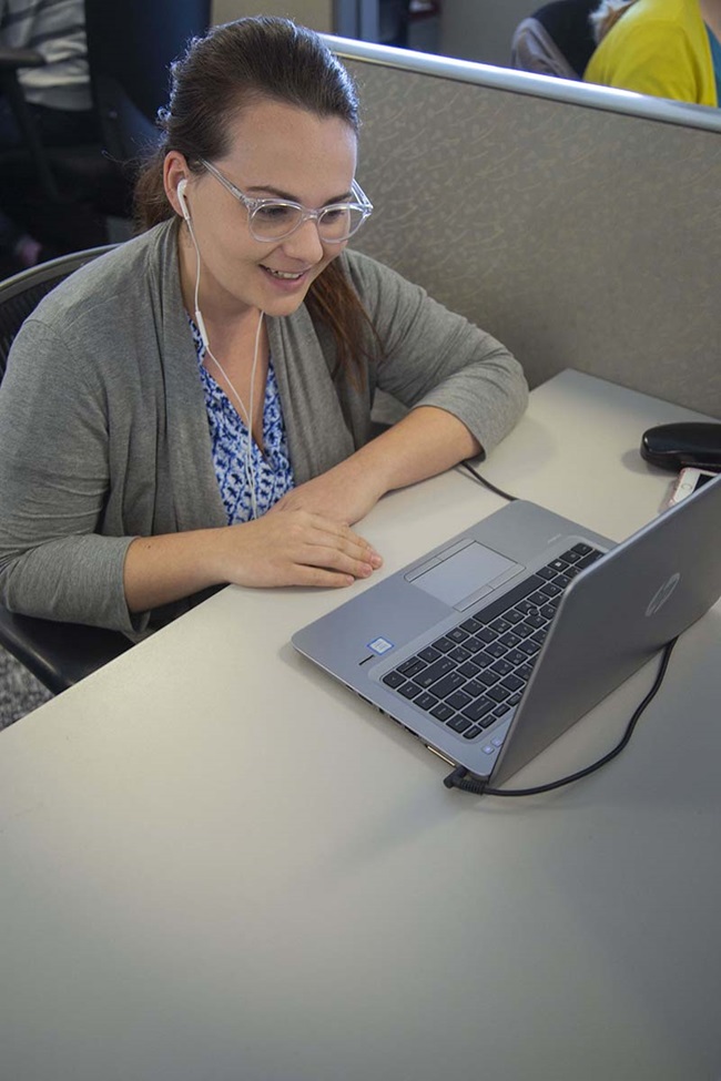 Woman smiling at computer in her office cubicle