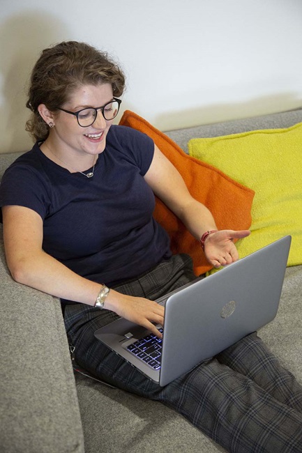 woman conversating on computer while relaxing on couch Nanci on C