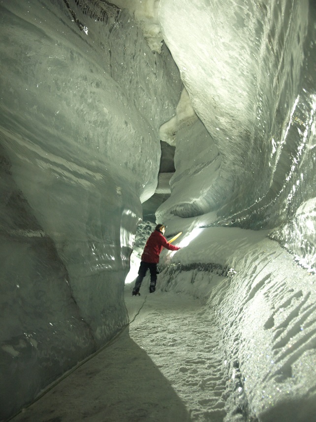 Glaciologist standing inside a glacial ice cave